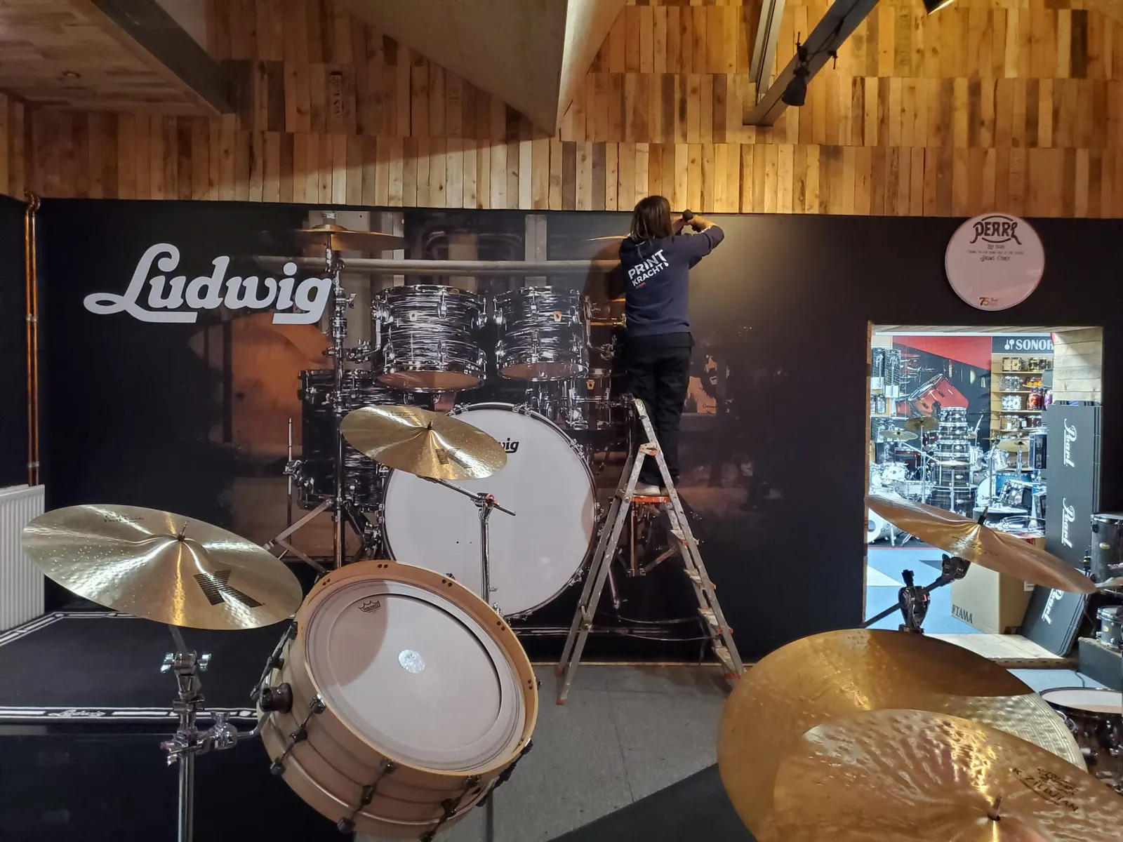 Muurvullende fotoprint op dibond-panelen met drumstel-motief in een muziekwinkel