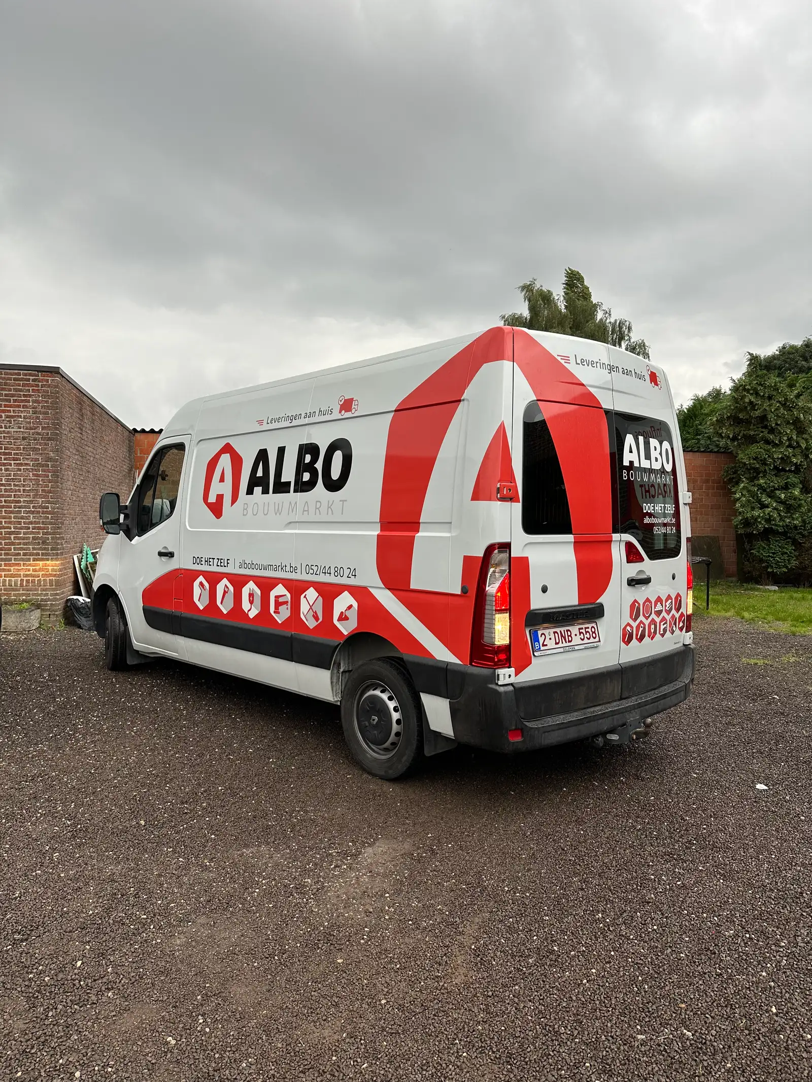 Bestelwagen met rood-witte huisstijlbelettering, schuin achteraanzicht na oplevering