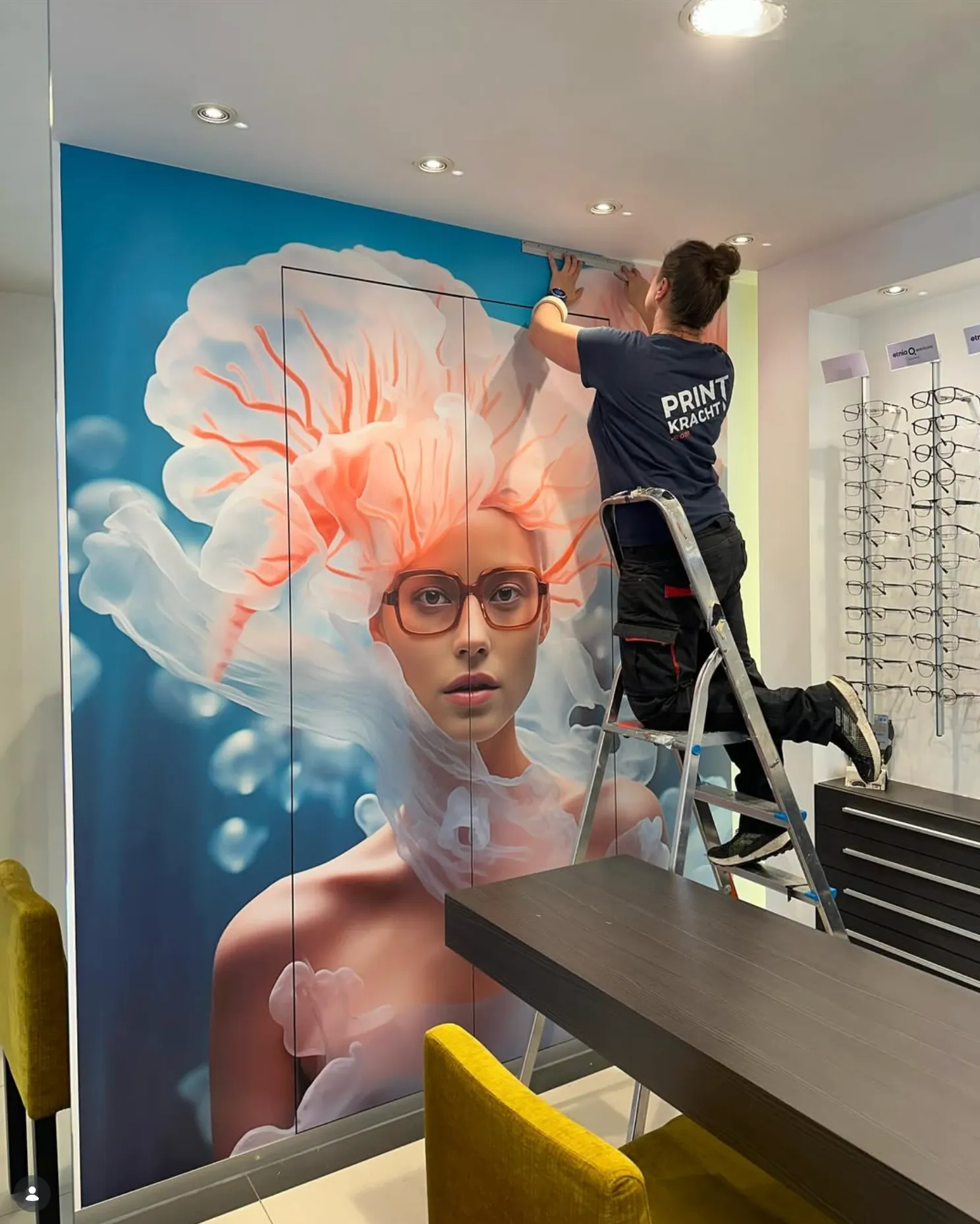 Medewerker beplakt een hoge kast met een fullcolor kwallen-print