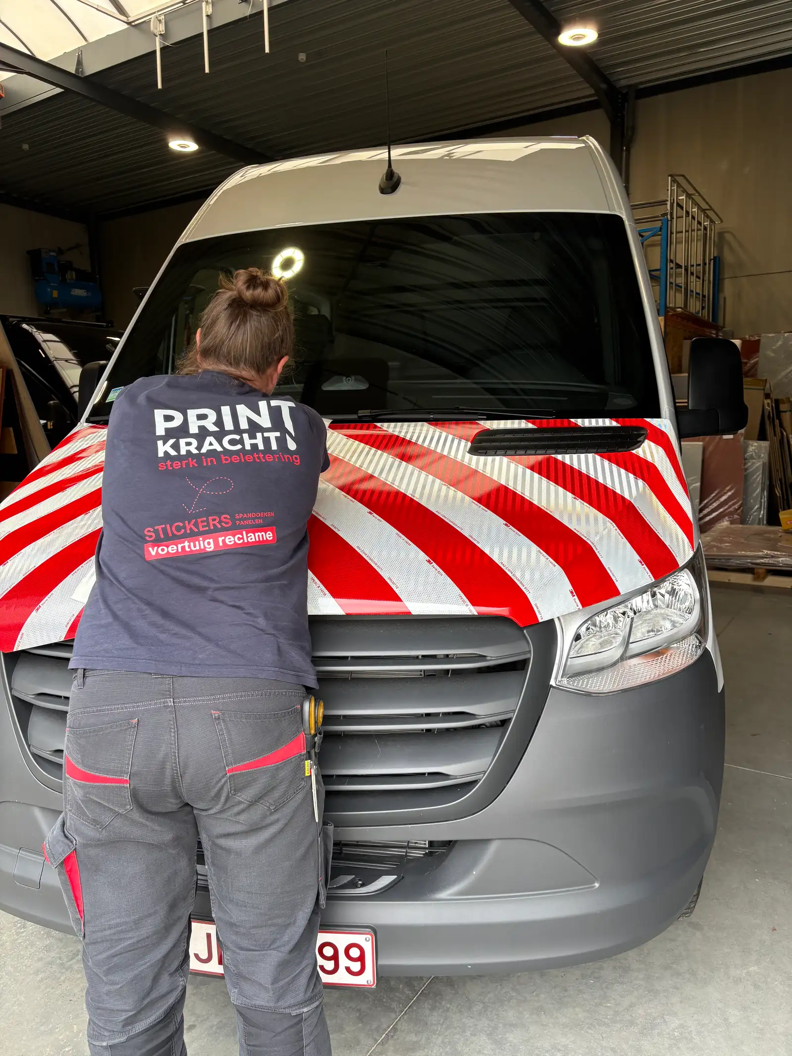 Printkracht-medewerker brengt reflecterende rood-witte chevronfolie aan op een motorkap