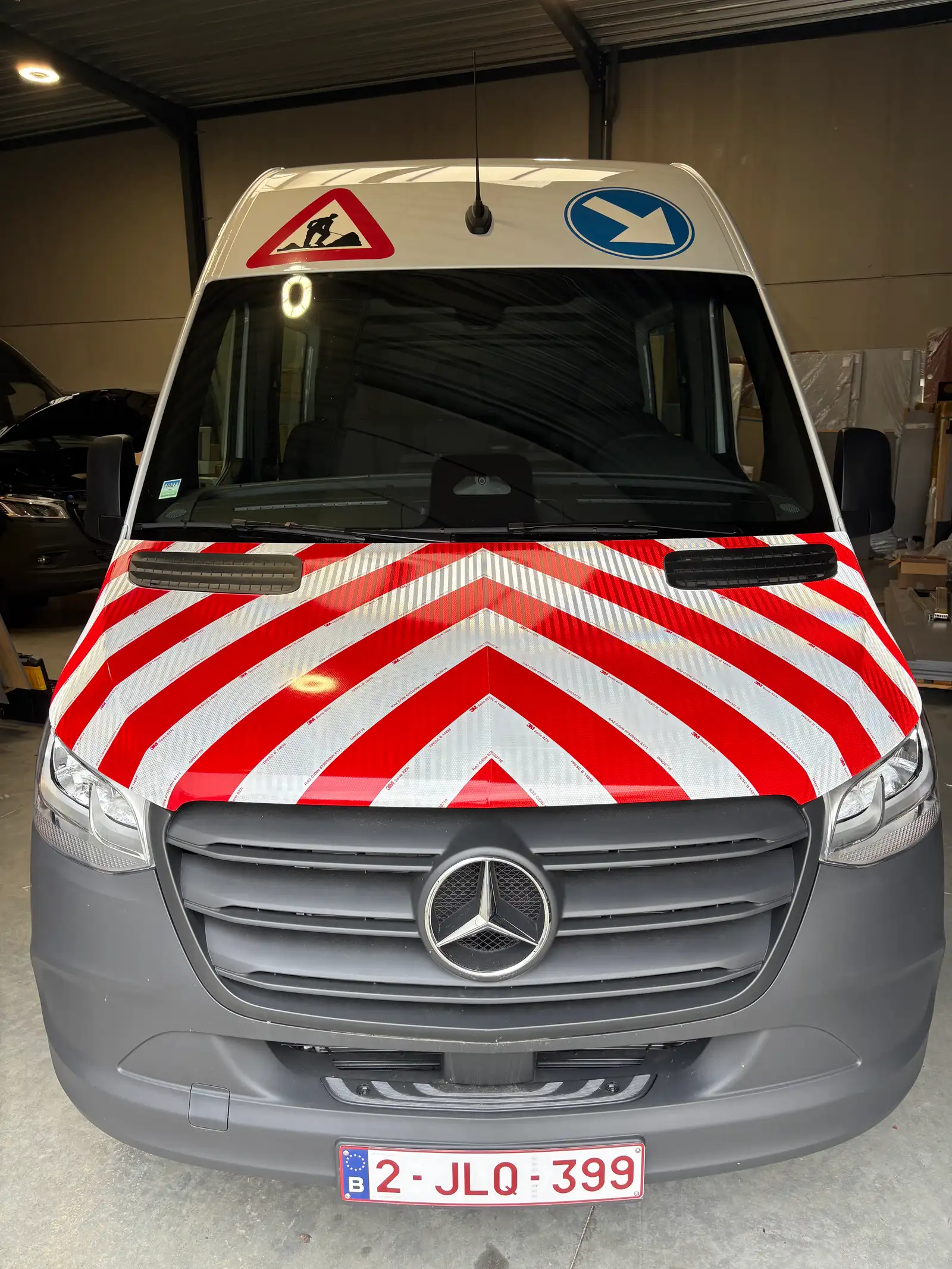 Bestelwagen met chevronmarkering op de motorkap en verkeersbord-stickers