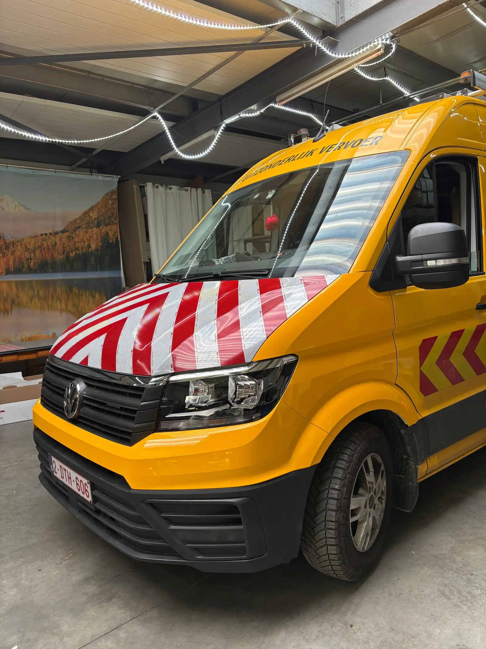 Gele camionette voor uitzonderlijk vervoer met rood-witte chevronmarkering op de motorkap