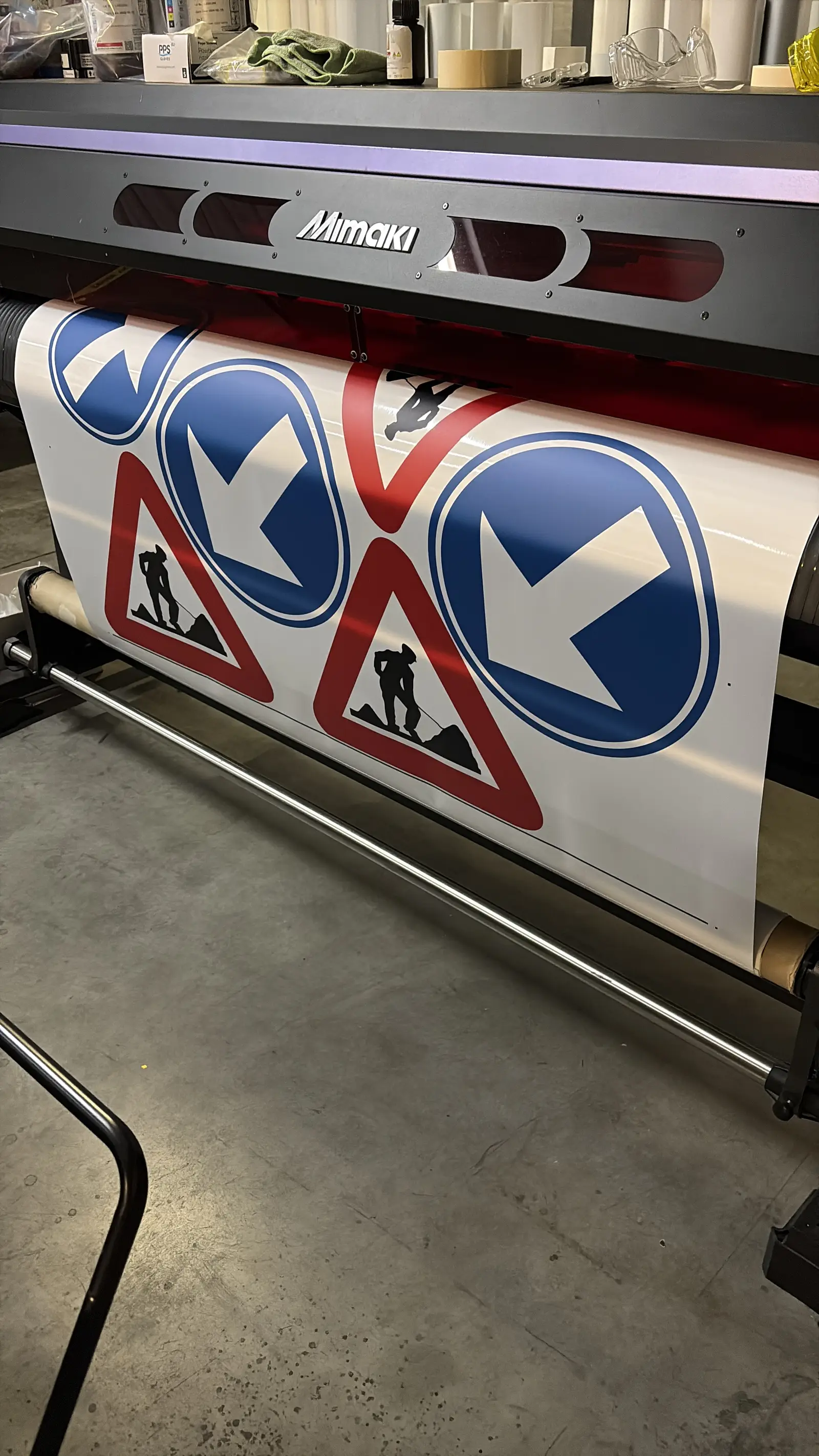 Vers geprinte reflecterende verkeersbord-stickers naast rood-witte chevronfolie in het atelier