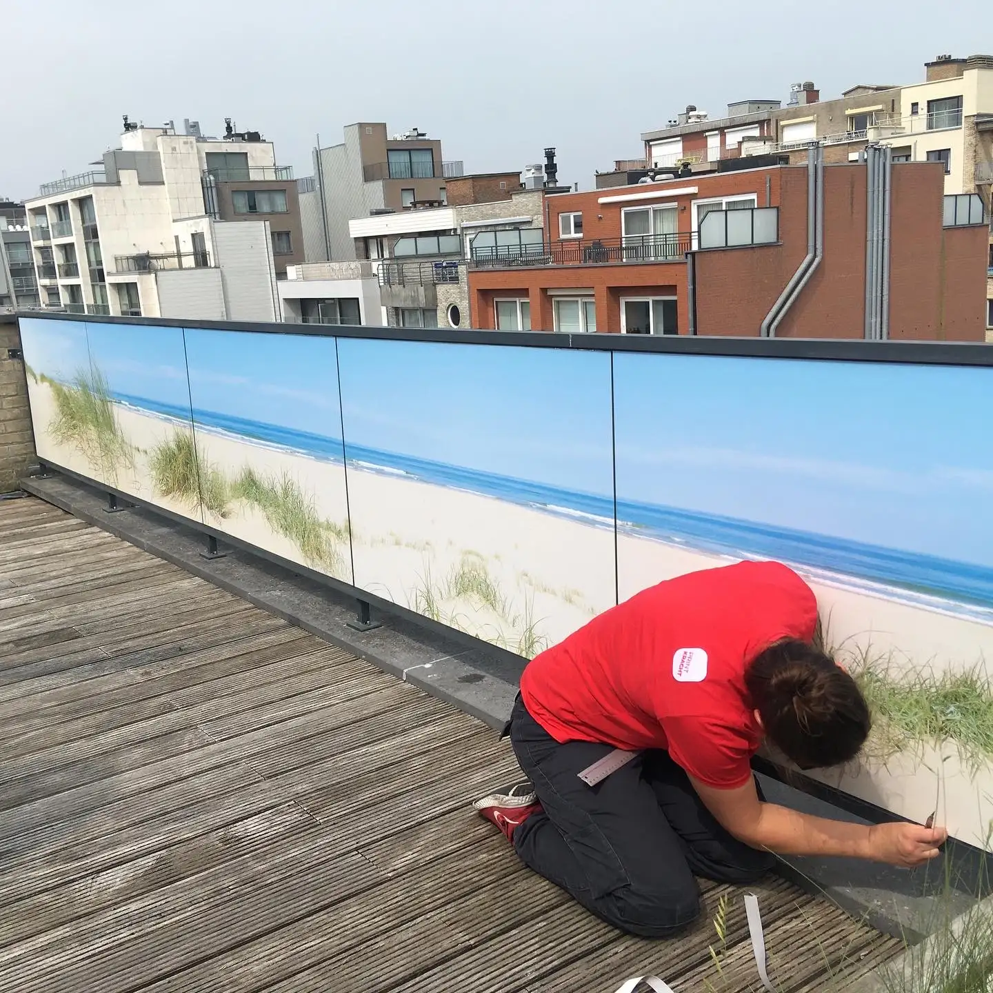 Montage van een bedrukte terrasomheining met duinen-motief aan de kust