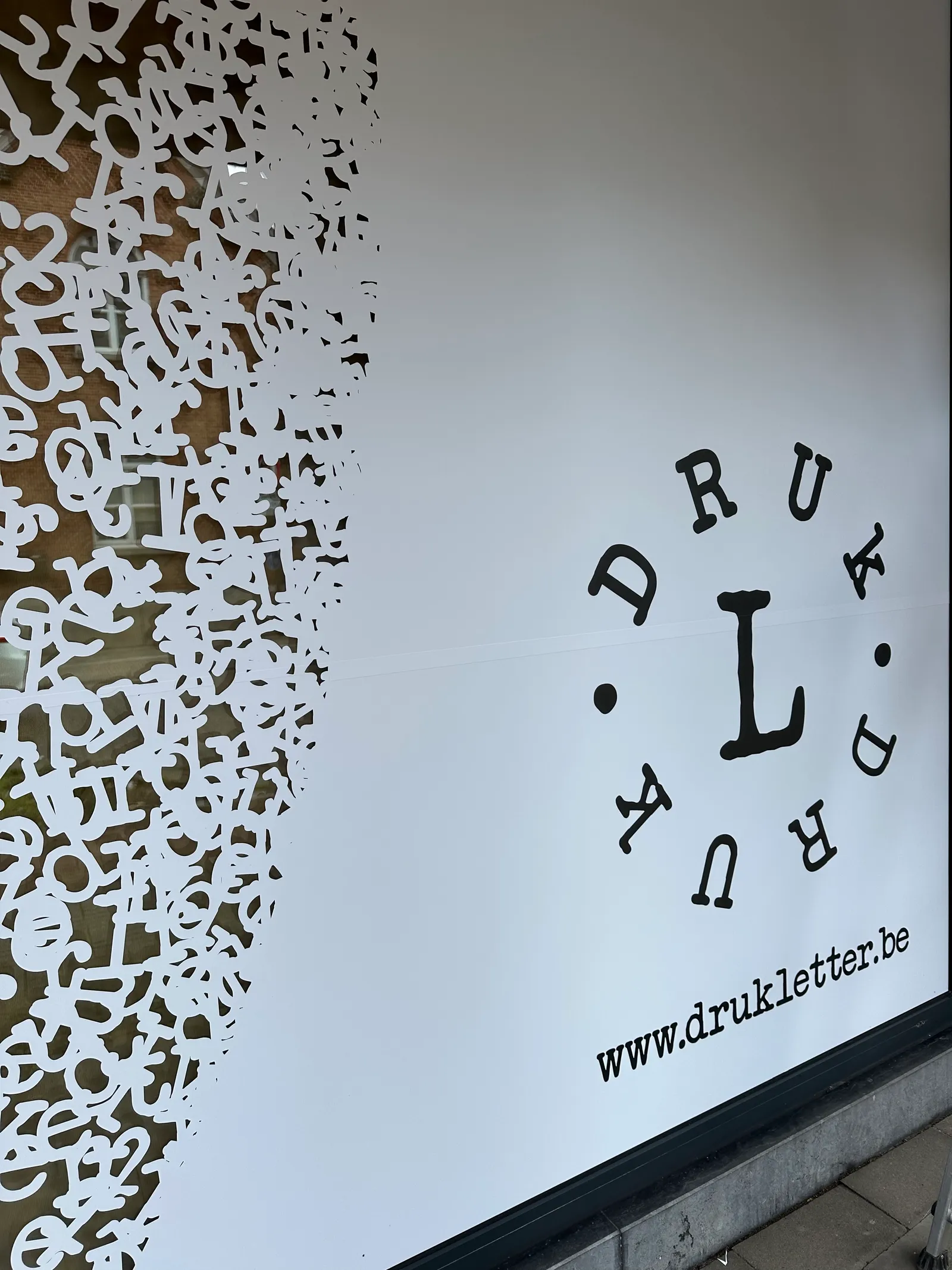 Gesneden witte vinylletters met logo op een etalageraam