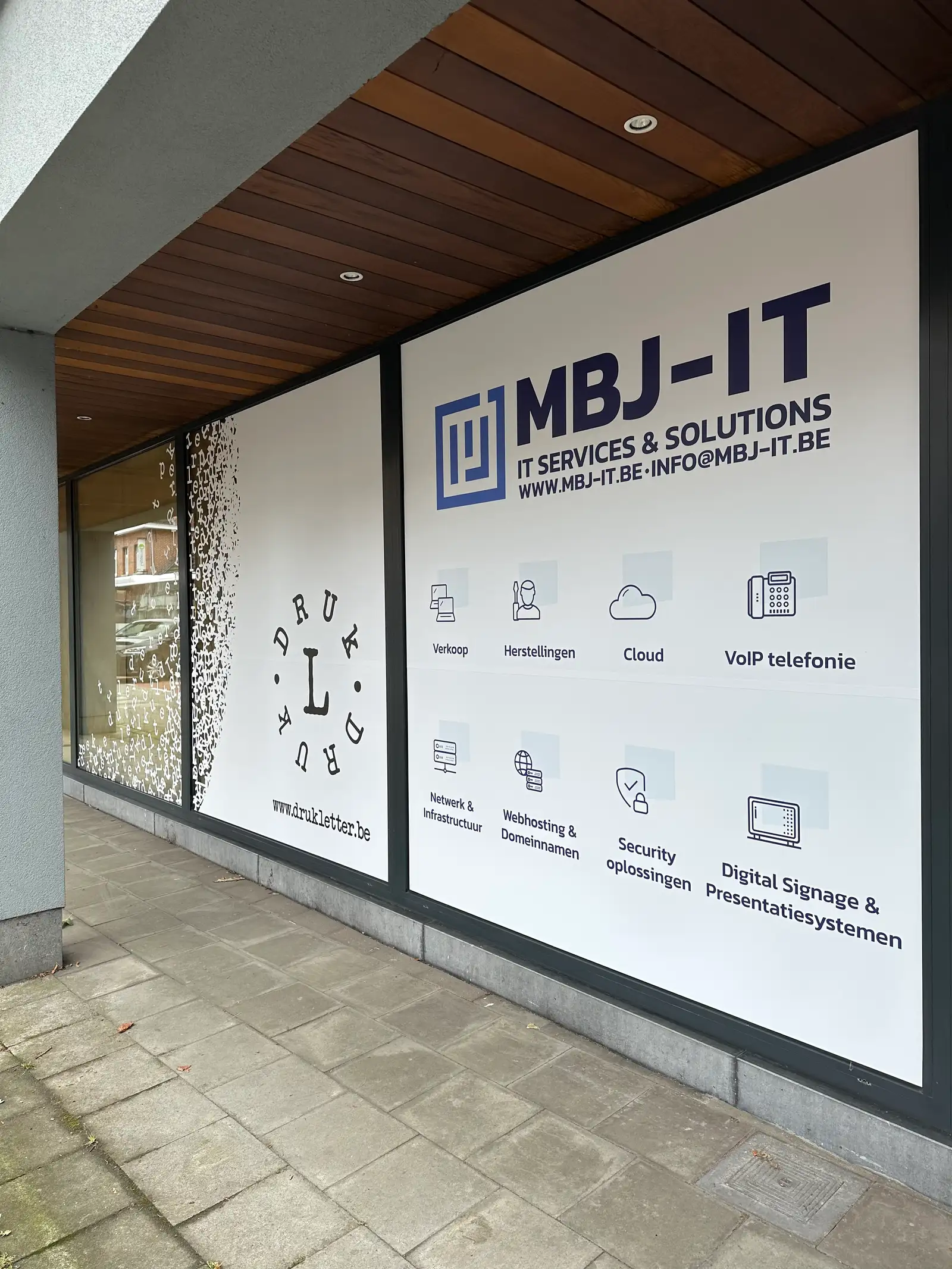 Kantoorgevel met fullcolor raambelettering met diensten-overzicht over de volledige vitrine