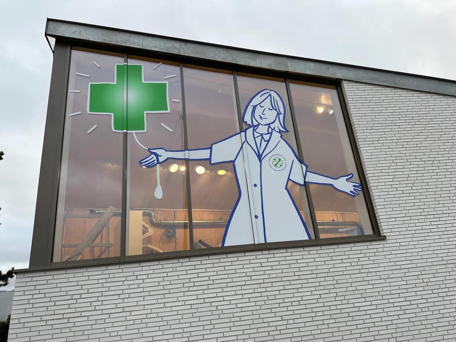 Tijdelijke raambelettering met apotheek-illustratie en opening-aankondiging