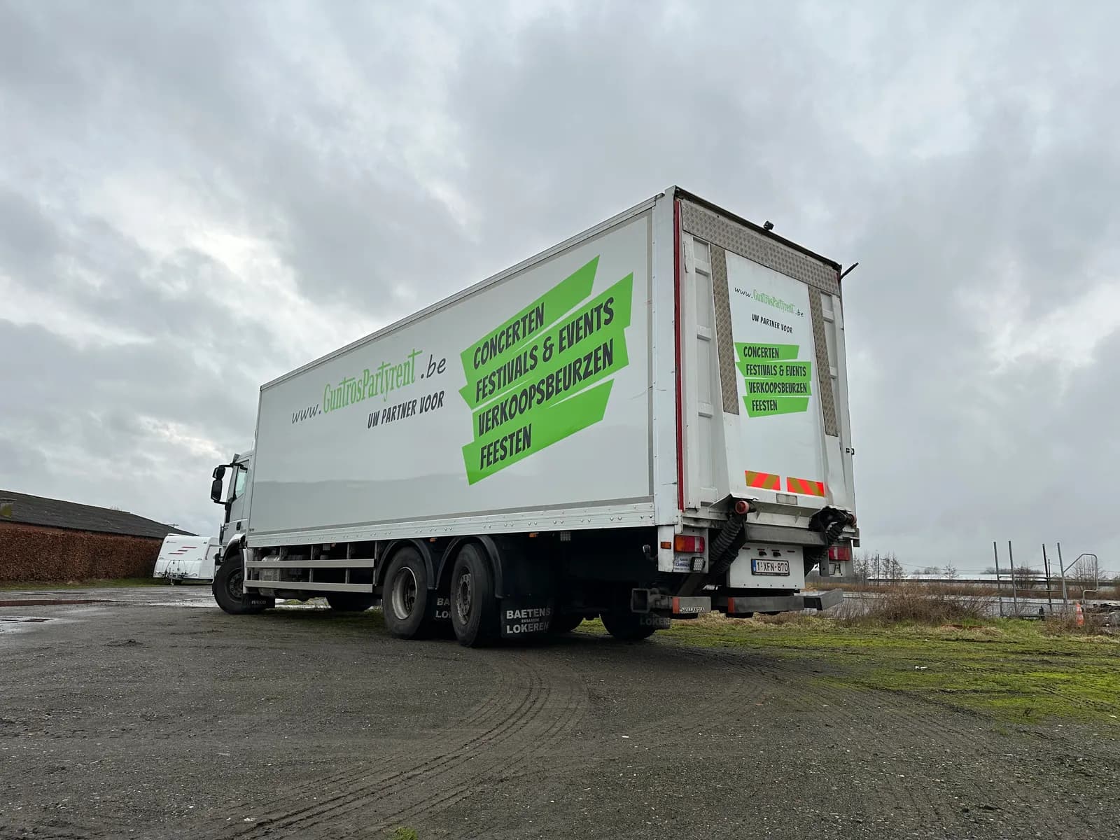 Vrachtwagentrailer met grote groene reclamebelettering, zijaanzicht