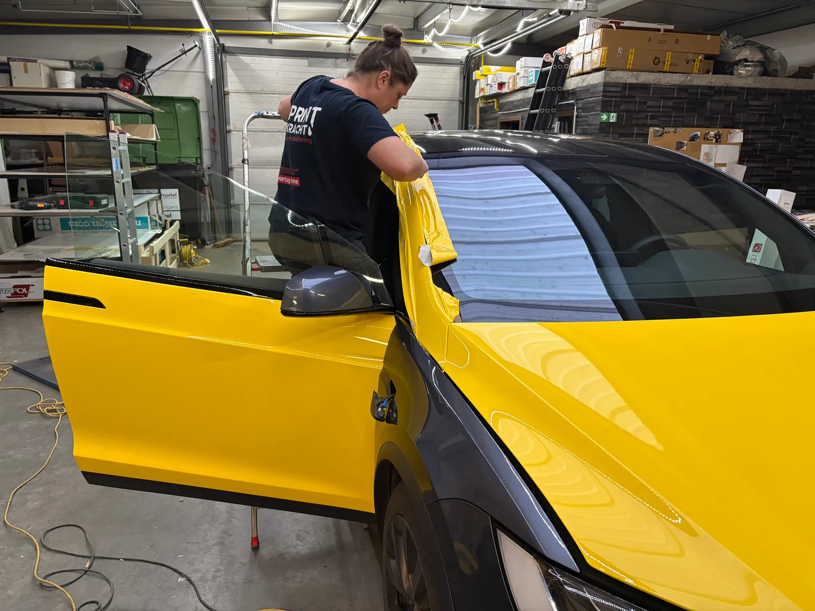 Montage van felgele 3M-wrapfolie op het portier van een elektrische wagen