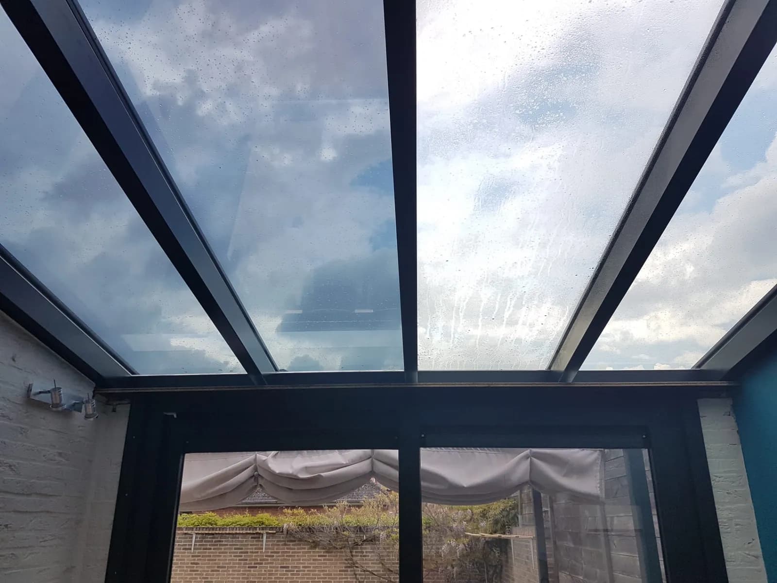 Verandadak half met en half zonder zonwerende folie: het verschil in lichtinval is meteen zichtbaar